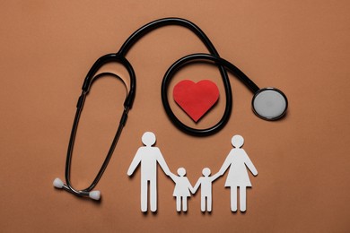 Paper family figures, red heart and stethoscope on brown background, flat lay. Insurance concept