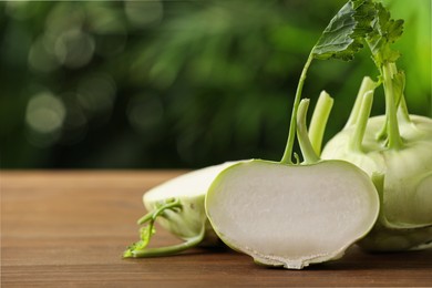 Whole and cut kohlrabi plants on wooden table. Space for text