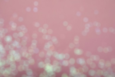 Blurred view of white glitter on pink background. Bokeh effect