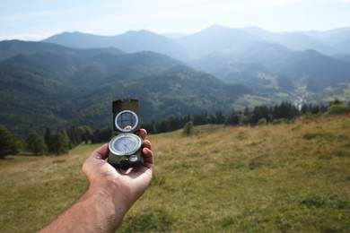 Man using compass during journey in mountains, closeup