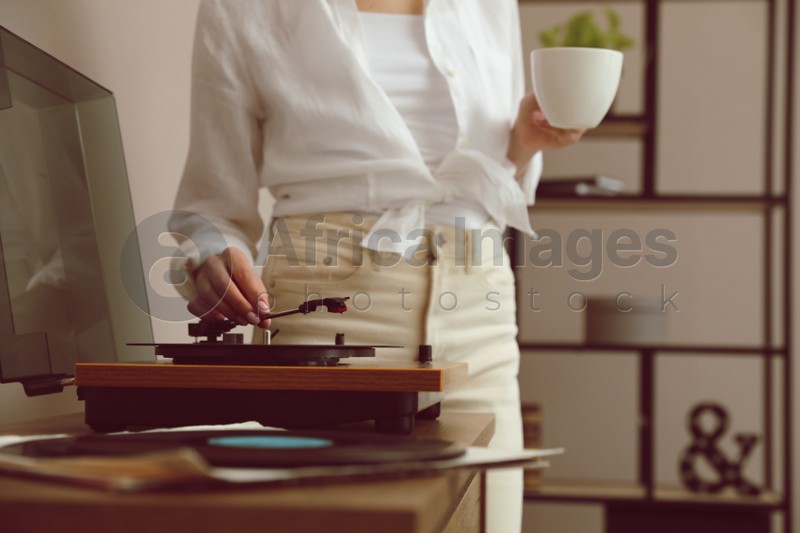 Woman using turntable at home, closeup view