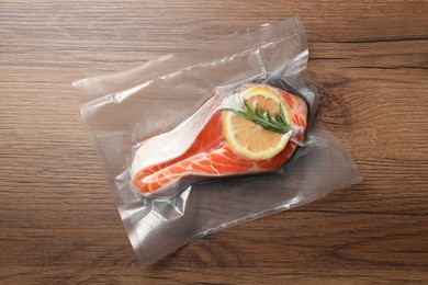 Salmon with lemon in vacuum pack on wooden table, top view