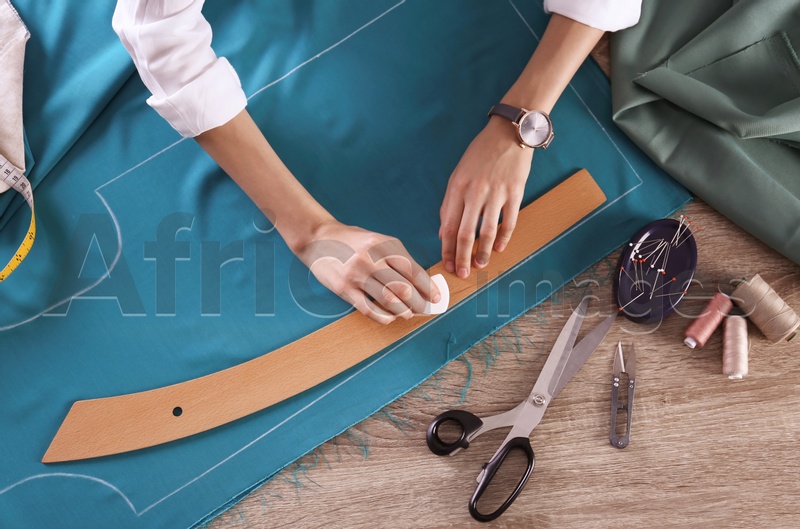 Photo of Tailor working with cloth at table in atelier, top view