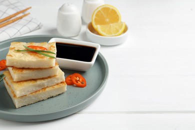 Photo of Delicious turnip cake with chili pepper and green onion on white wooden table, space for text