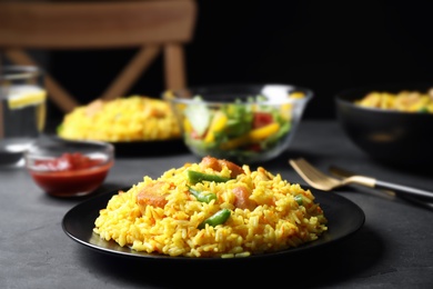Delicious rice pilaf with meat served on dark table, closeup. Space for text