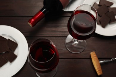 Tasty red wine and chocolate on wooden table, above view