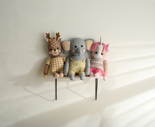 Shelf with cute toys on light wall. Baby room interior element