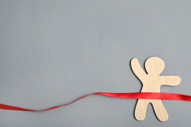Wooden man and red ribbon on grey background, top view with space for text. Victory concept