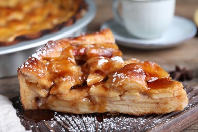 Photo of Slice of traditional apple pie on wooden board, closeup