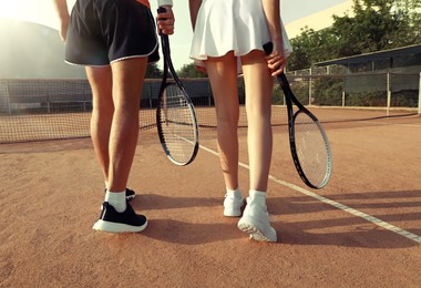 Couple with tennis rackets at court on sunny day, closeup