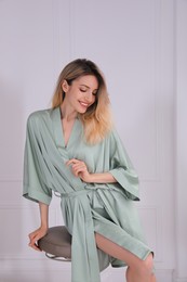 Pretty young woman in beautiful silk robe sitting on stool at home