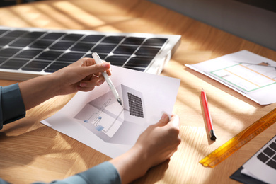 Woman working on house project with solar panels at table in office, closeup