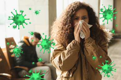 Young African-American woman sneezing indoors. Dangerous virus