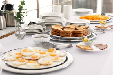 Clean dishware and different meals for breakfast on white table indoors. Buffet service