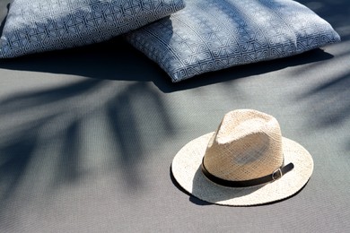 Photo of Stylish straw hat and pillows on grey fabric outdoors, space for text