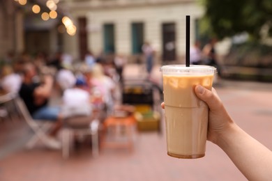 Woman holding takeaway plastic cup with cold coffee drink outdoors, closeup. Space for text