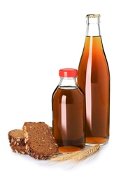 Photo of Glass bottles of delicious kvass, spikelets and bread slices on white background. Refreshing drink