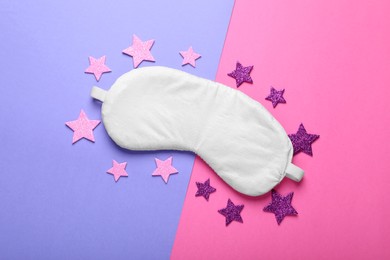 Photo of Soft sleep mask and confetti in shape of stars on color background, flat lay