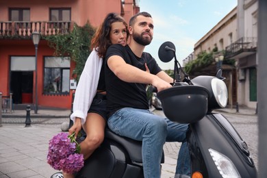 Beautiful young couple riding motorcycle on city street