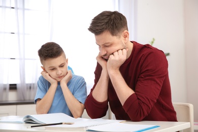 Dad helping his son with difficult homework assignment in room
