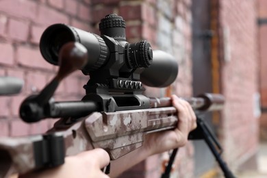Soldier holding modern powerful sniper rifle with telescopic sight outdoors, closeup