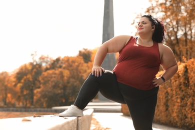 Beautiful overweight woman doing sport exercises in park