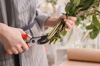 Female florist pruning stems at workplace, closeup