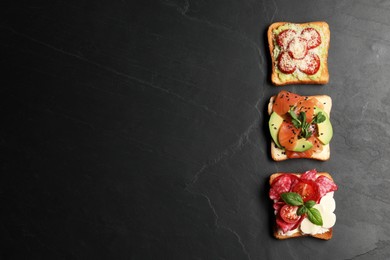 Tasty toasts with different toppings on black table, flat lay. Space for text