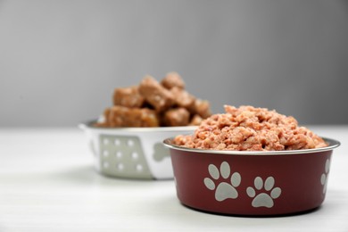 Wet pet food in feeding bowl on white table, space for text