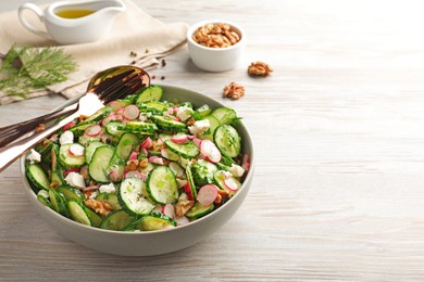 Delicious cucumber salad served on white wooden table. Space for text