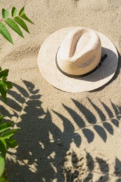 Stylish straw hat on sand outdoors, above view