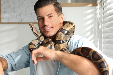 Man with his boa constrictor at home. Exotic pet