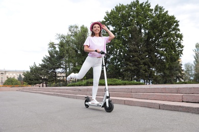 Young woman riding electric kick scooter on city street