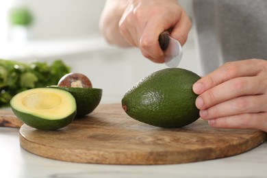 Photo of Man cutting avocado for delicious smoothie at white table, closeup