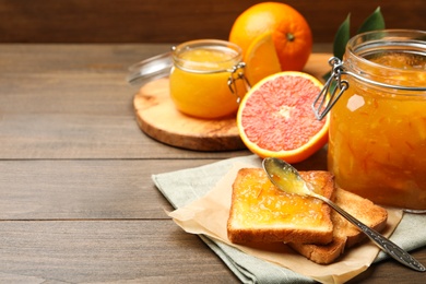Delicious toasts, orange marmalade and fresh fruits on wooden table. Space for text