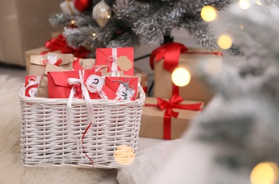 Basket full of gifts in paper bags for Christmas advent calendar on floor