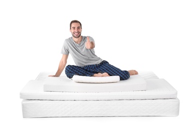Young man sitting on mattress pile against white background