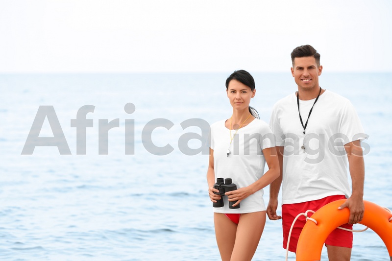 Professional lifeguards with life buoy and binocular at beach