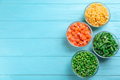 Different frozen vegetables on light blue wooden table, flat lay. Space for text