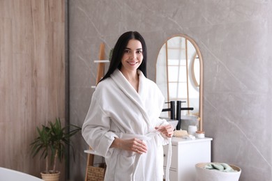 Beautiful young woman wearing soft white robe in bathroom