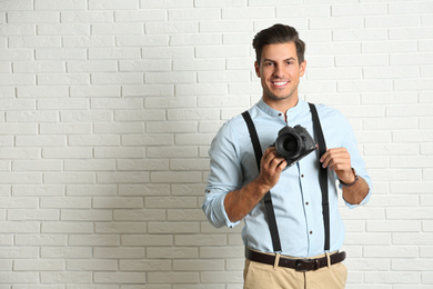 Professional photographer working near white brick wall in studio. Space for text