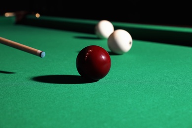 Striking red billiard ball with cue on table