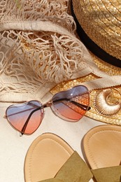Flat lay composition with stylish sunglasses and other fashionable accessories on sand