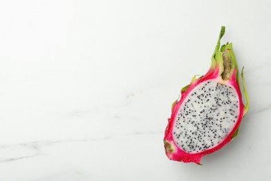 Photo of Half of delicious dragon fruit on white marble table, top view. Space for text