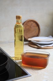 New and used cooking oil near stove on kitchen counter