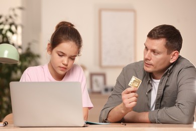 Father talking with his teenage daughter about contraception while she using laptop at home. Sex education concept