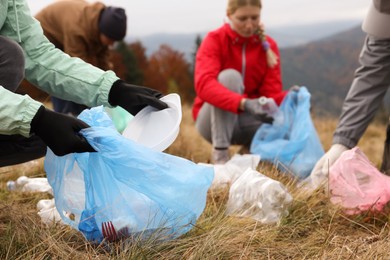 People with trash bags collecting garbage in nature