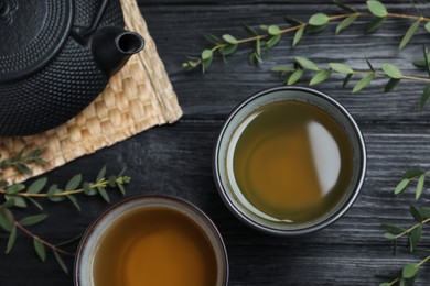 Aromatic eucalyptus tea on black wooden table, flat lay