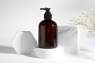 Bottle of shampoo and flowers on white background