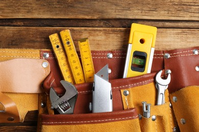 Photo of Belt with utility knife and different tools on wooden table, top view